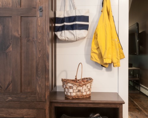 A wooden bench with baskets and bags hanging on it.