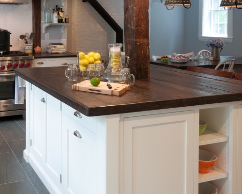 A kitchen with white cabinets and wooden counter tops.