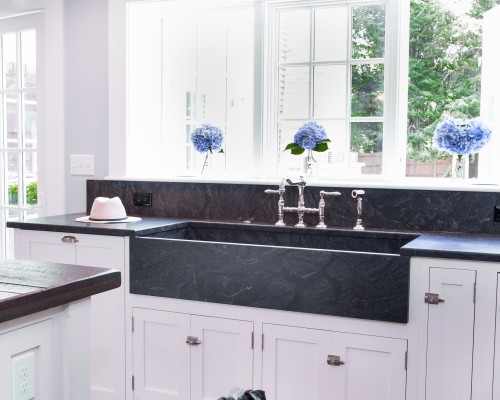 A dog sitting in front of a sink.