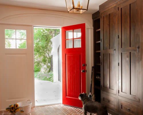 A dog standing in front of a red door.