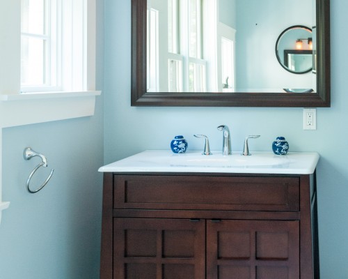 A bathroom with blue walls and white counter tops.