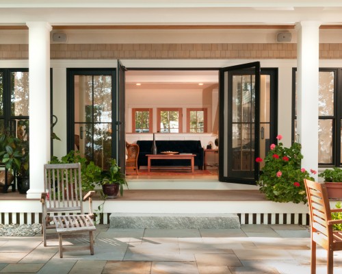 A patio with two chairs and an open door.