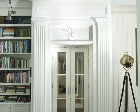 A white door in the center of a room with bookcases.