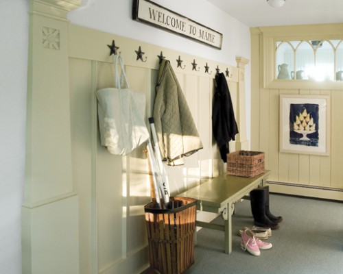 A hallway with a bench, coat rack and umbrella.