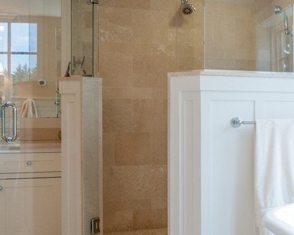 A bathroom with a walk in shower and white cabinets.