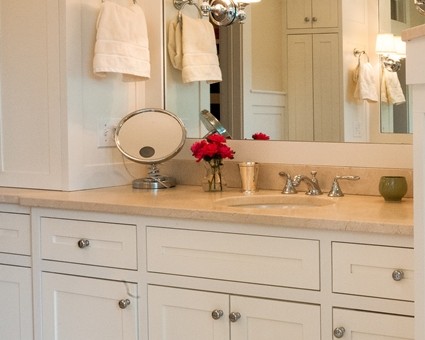 A bathroom with white cabinets and a large mirror.