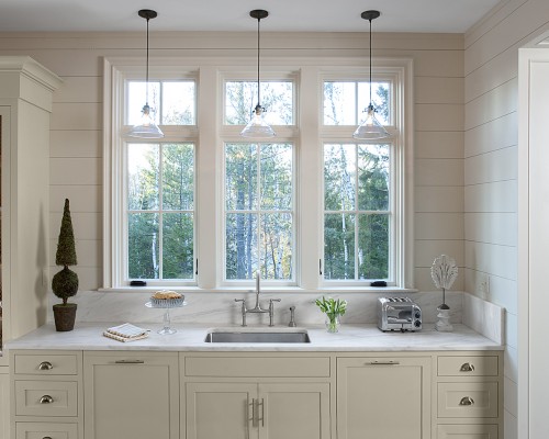 A kitchen with three windows and a sink.