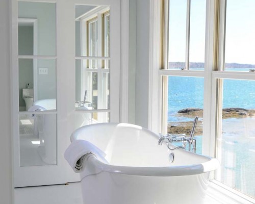 A bathroom with a tub and a window overlooking the ocean.