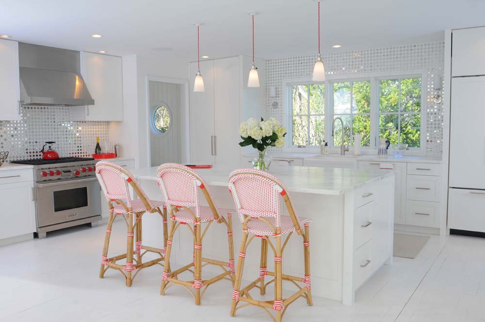 A kitchen with three pink chairs and white counters.