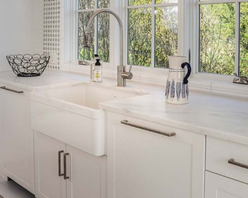 A white kitchen with a sink and window