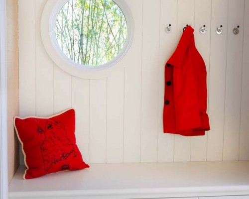 A red pillow and coat hanging on the wall.